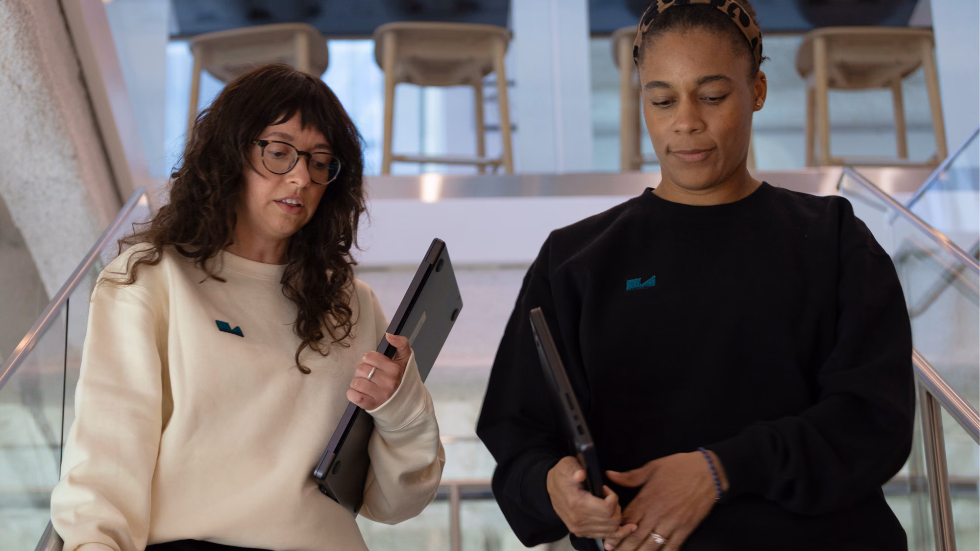 Two colleagues carrying laptops while walking down a set of stairs in Verily office space.